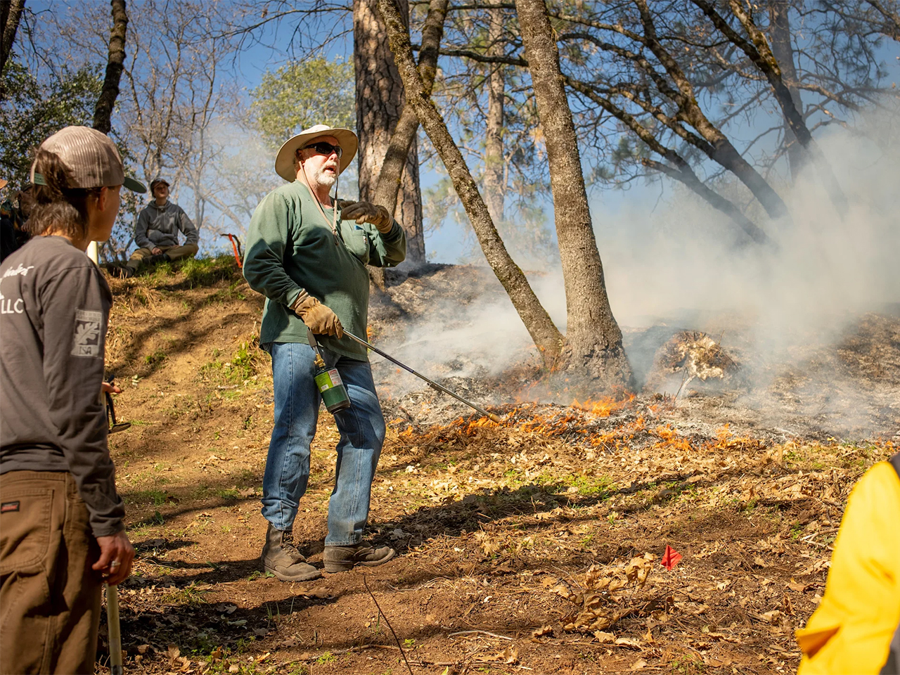Chris Paulus talks to group in wooded clearing during a prescribed burn