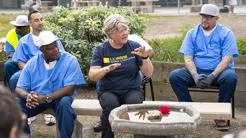 Woman speaking to group seated around a garden
