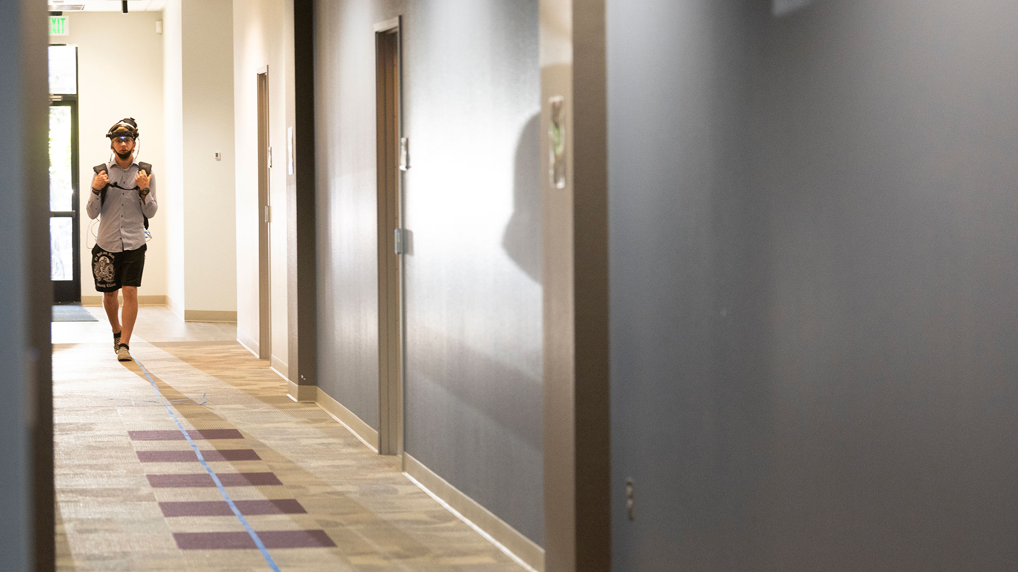 Man in tracking technology walks down a hallway.