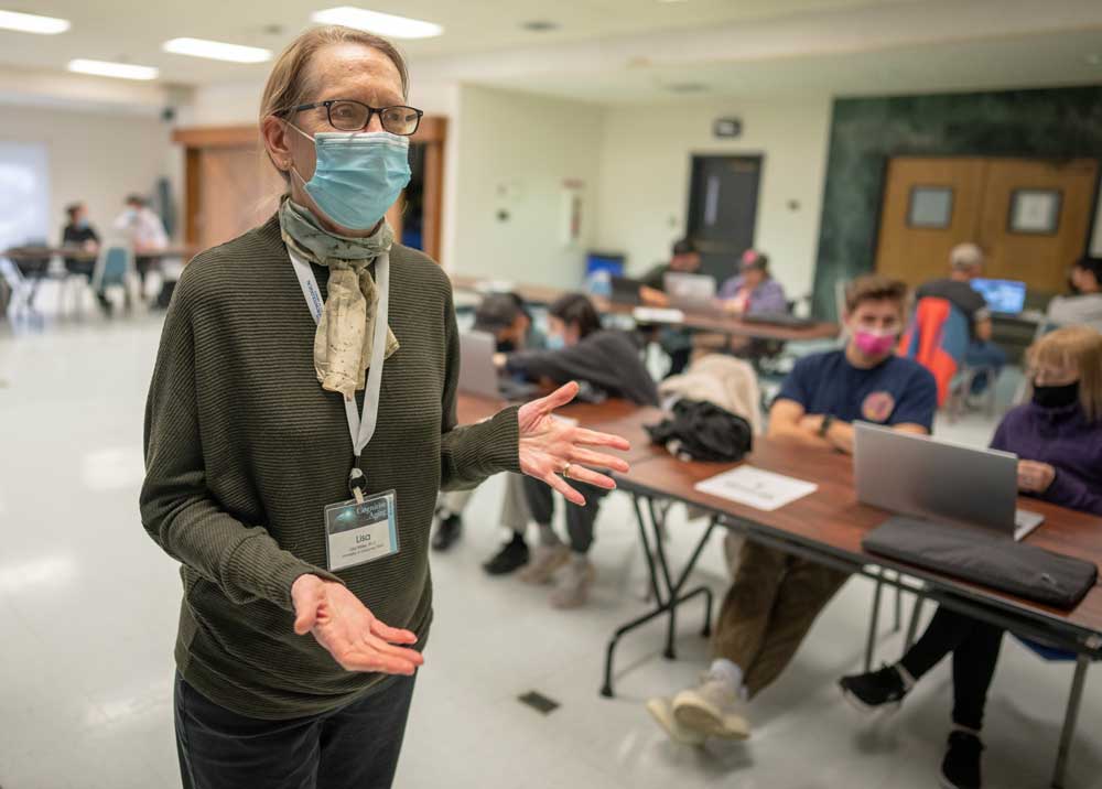 Faculty woman with blong hair in UC Davis classroom with students seated at computers in background