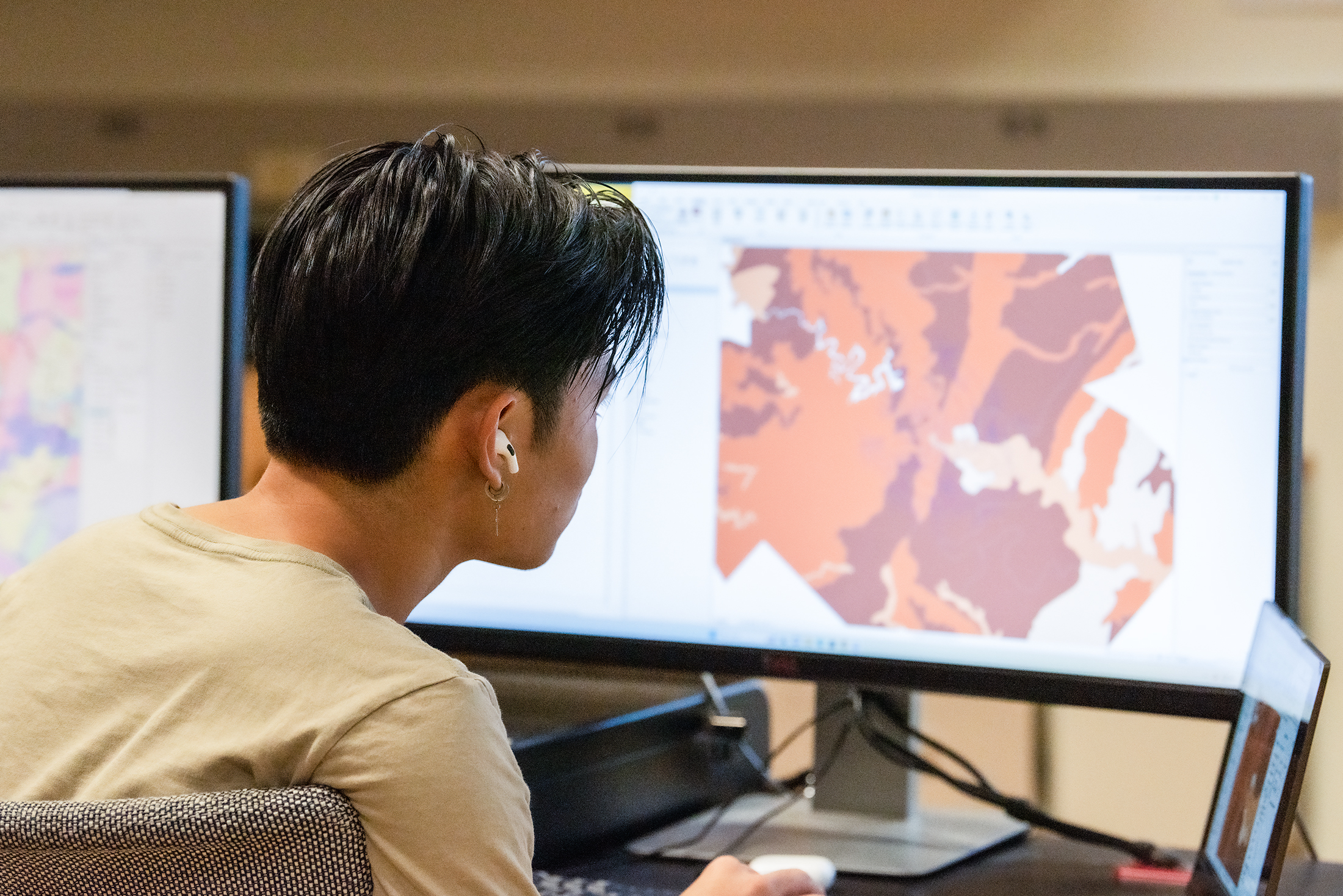 A student examines a map, in shades of orange and red, on a computer screen.
