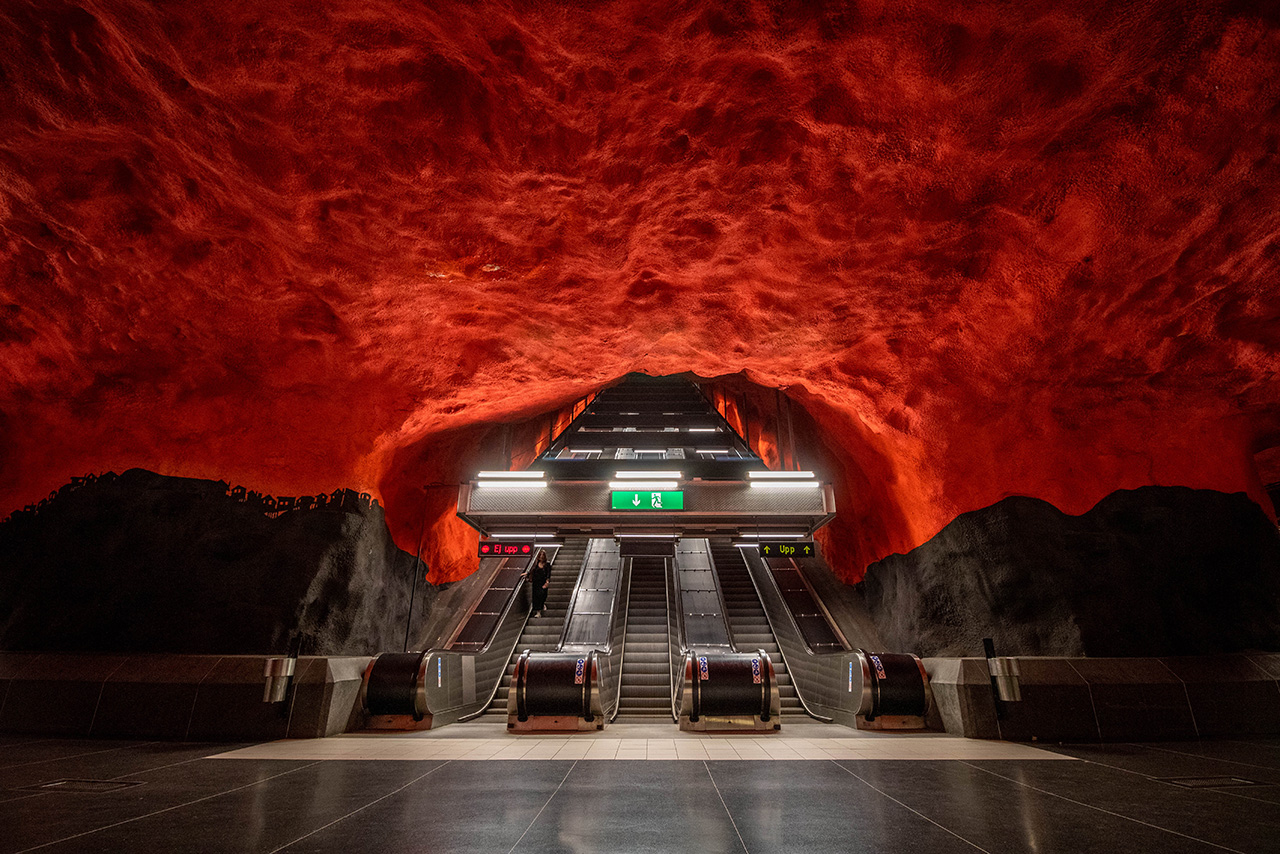 Escalator passes through red ceiling.