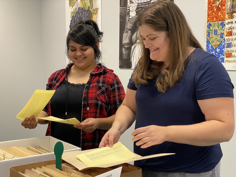 A student smiles while filing documents with a coworker at UC Davis. 