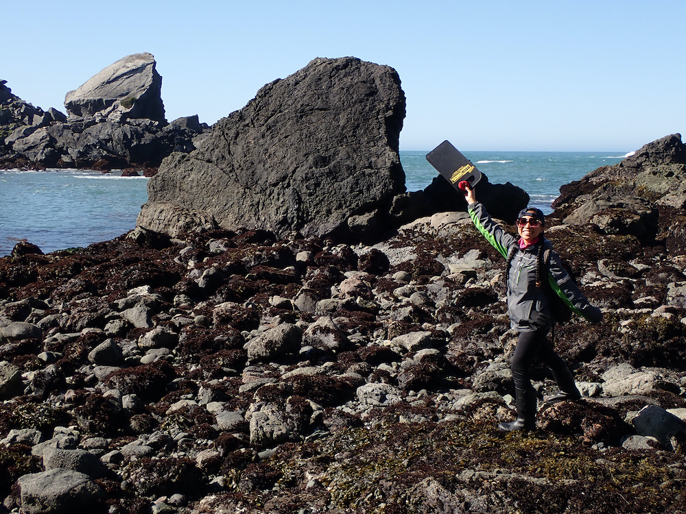 Jacquie Rajerison holds up a find at the tide pools in front of the ocean.