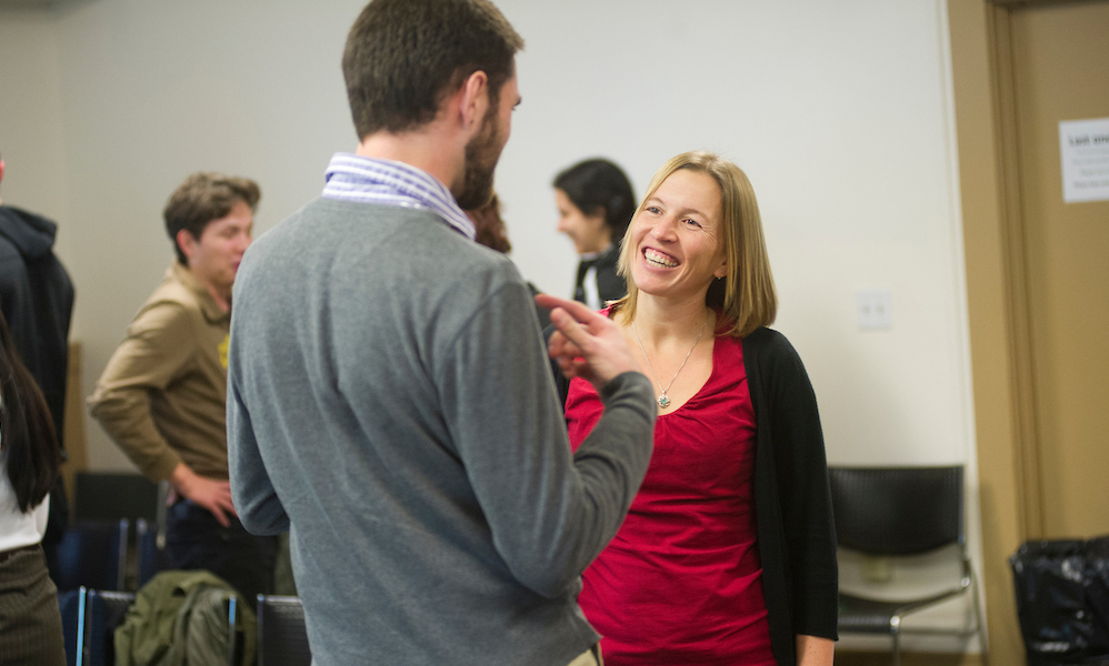 Two students smile at each other while standing up at UC Davis.