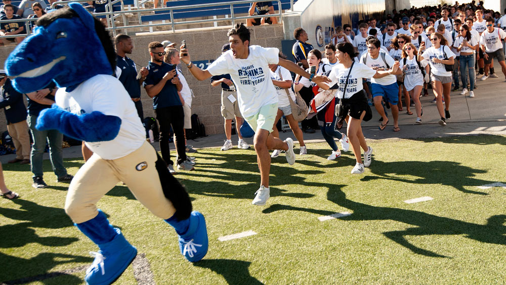 Students run on to the football field before the first home game