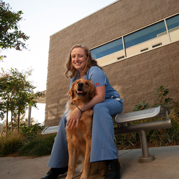A veterinary student cares for a dog outside of the UC Davis School of Veterinary Medicine