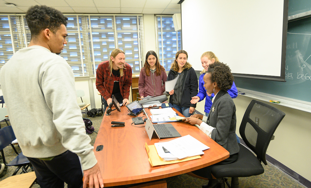 A professor talks with students around a desk at UC Davis.