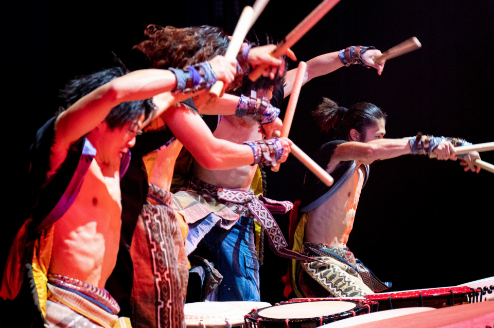 Taiko ensemble in costume performing on stage