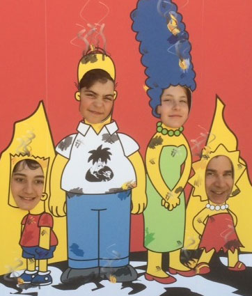 Four faces seen through Simpsons-Mr. Burns cutout board.