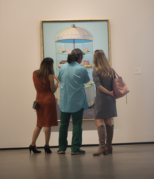 Three museum visitors gaze at a painting.