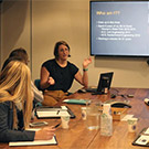 Woman in conference room speaks to students.