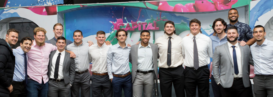 Student-athletes in dress shirts, some with ties and jackets, in a line