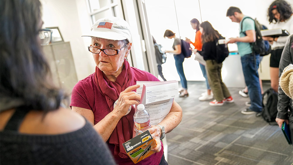 Woman holding forms talks to student.