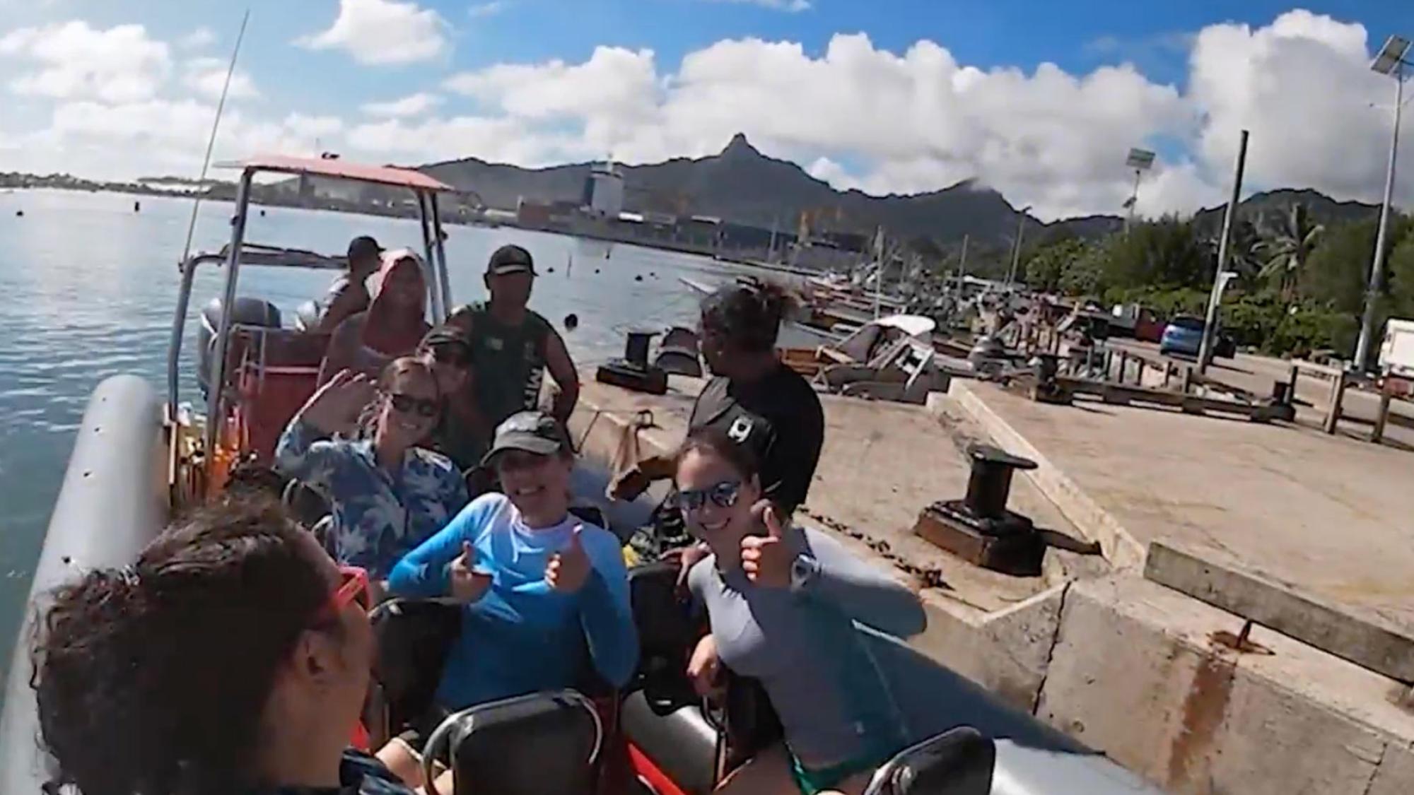 A group of researchers waving from a skiff