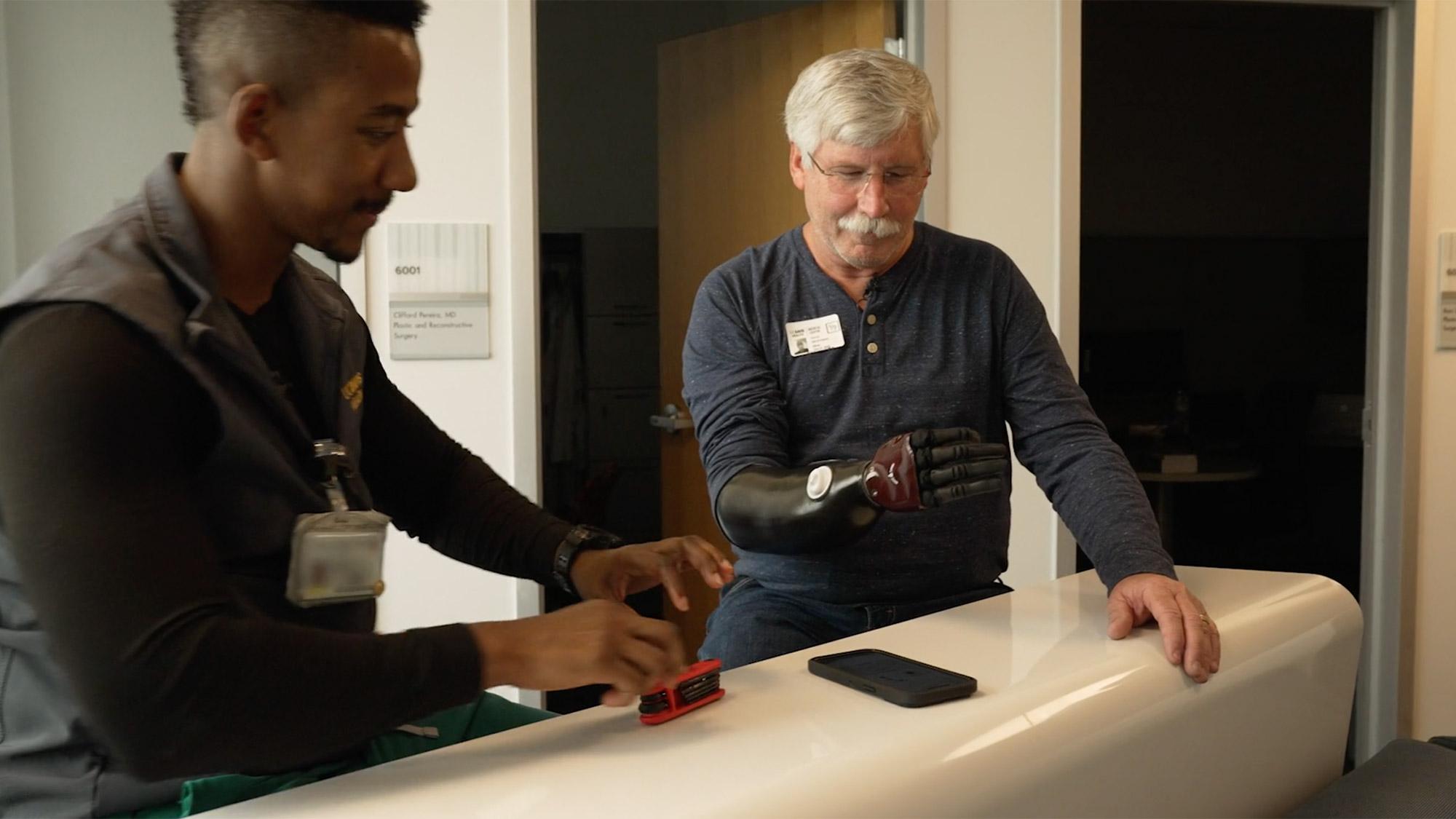 David Brockman, a retired CalFire captain, and UC Davis Health certified prosthetist orthotist Laduan Smedley test out prosthetic arm