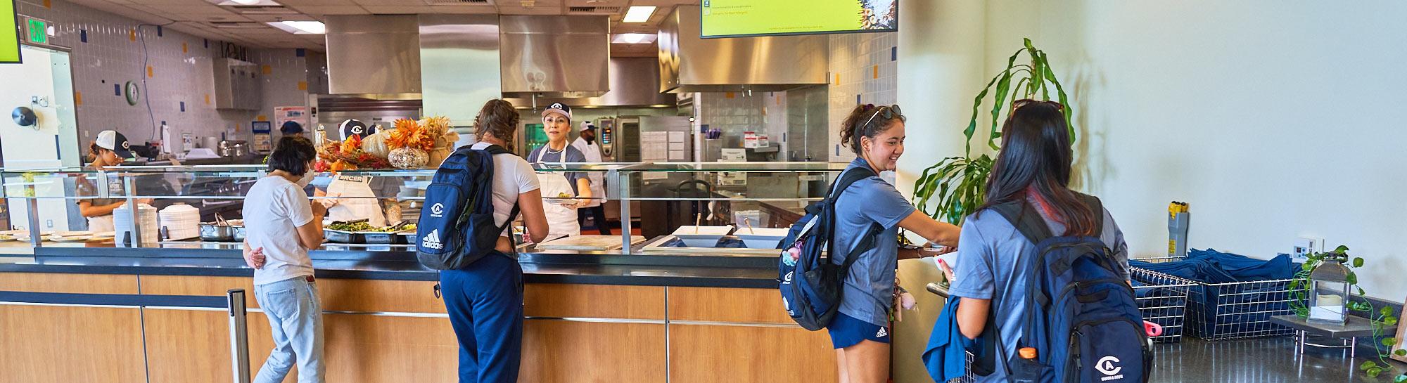 Busy café counter with staff serving customers in backpacks