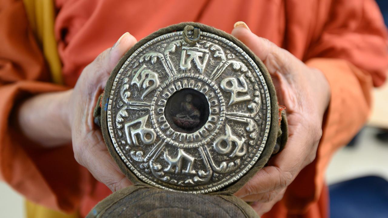 A monk holds a votive tablet at UC Davis.