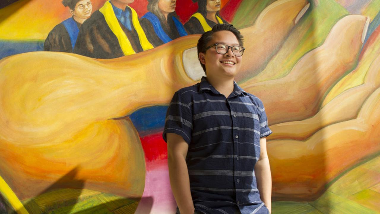 Alex San Pablo in front of wall at student community center