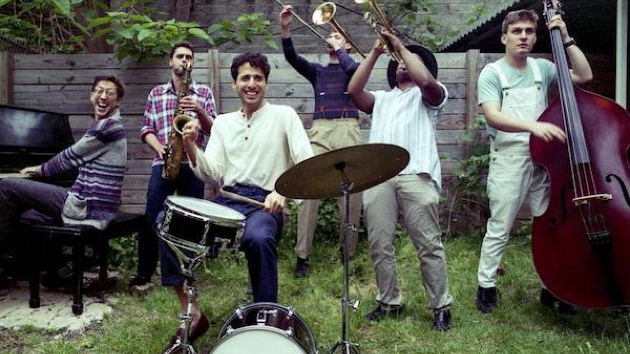 Sammy Miller and the Congregation joyfully playing theor musical instruments in a grassy backyard.