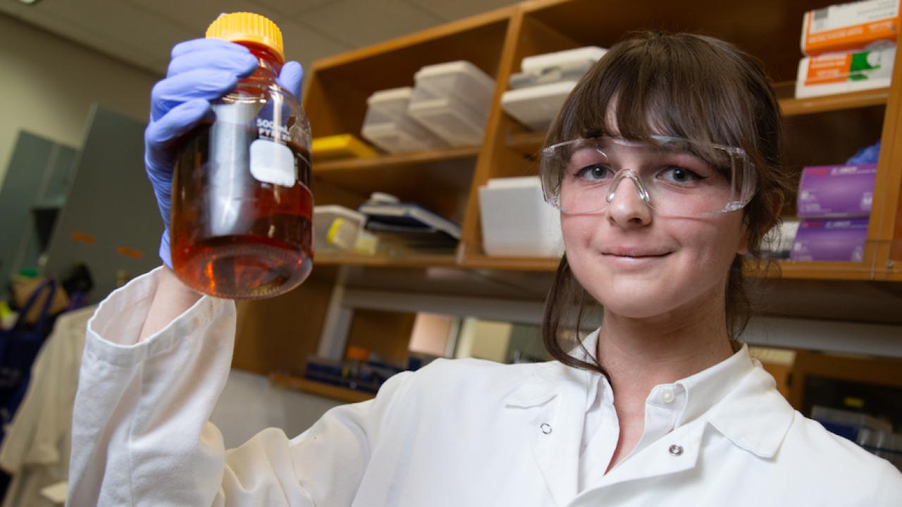 Lynne Hagelthorn holds up a vial in a lab. 