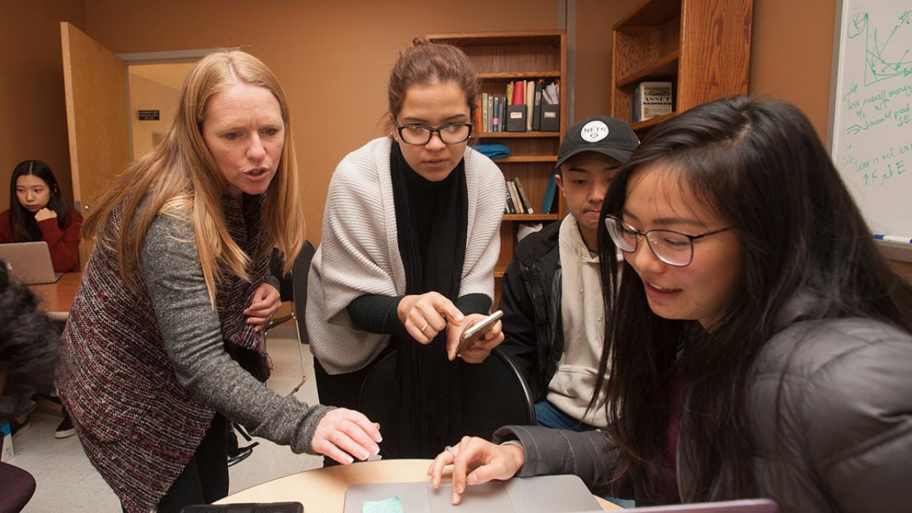 Economics lecturer Janine Wilson discusses a theory with Andrea Romero, Daniel Moon and Julia Tien, all economics majors