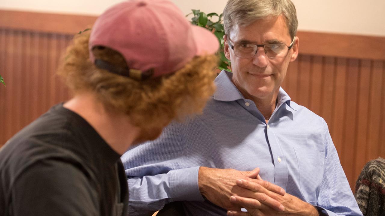 Student in a baseball cap facing a male parent in a discussion