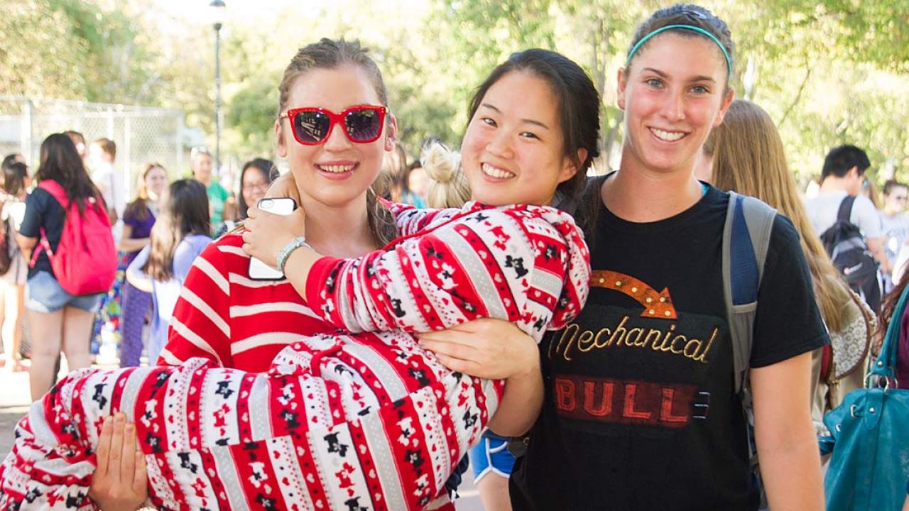 Three women in pajamas with one in the arms of another