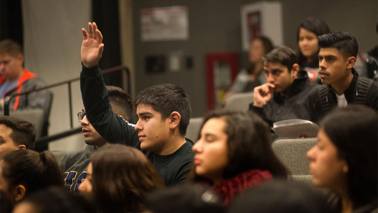 a male high school student raises a hand to ask question