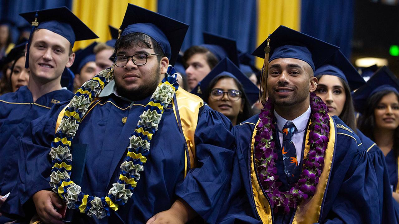 Men sit at commencement ceremony.