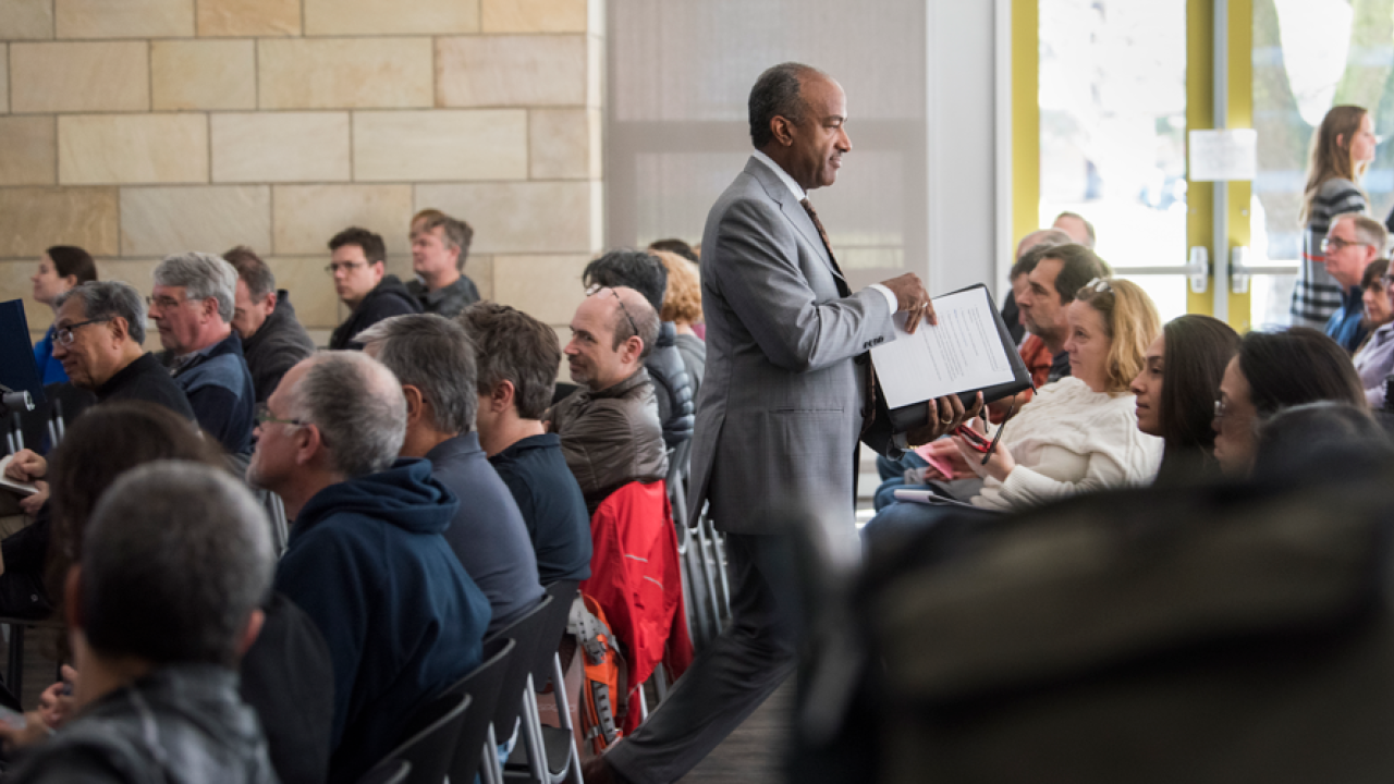 Chancellor May walks in aisle of Academic Senate meeting, holding his remarks.