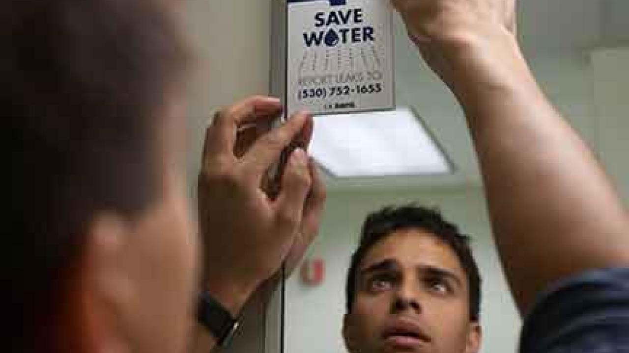 Photo: Student Jordan Ramalingam affixes a "Save Water" cling to a bathroom mirror.