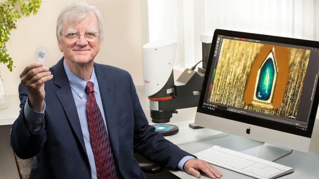 Scientist in front of computer holding vaccine patch device