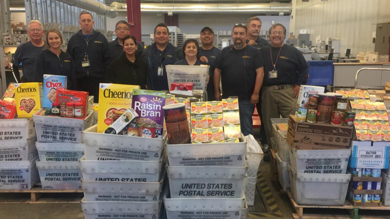 Mail Services crew, lined up behind mail bins full of donated food