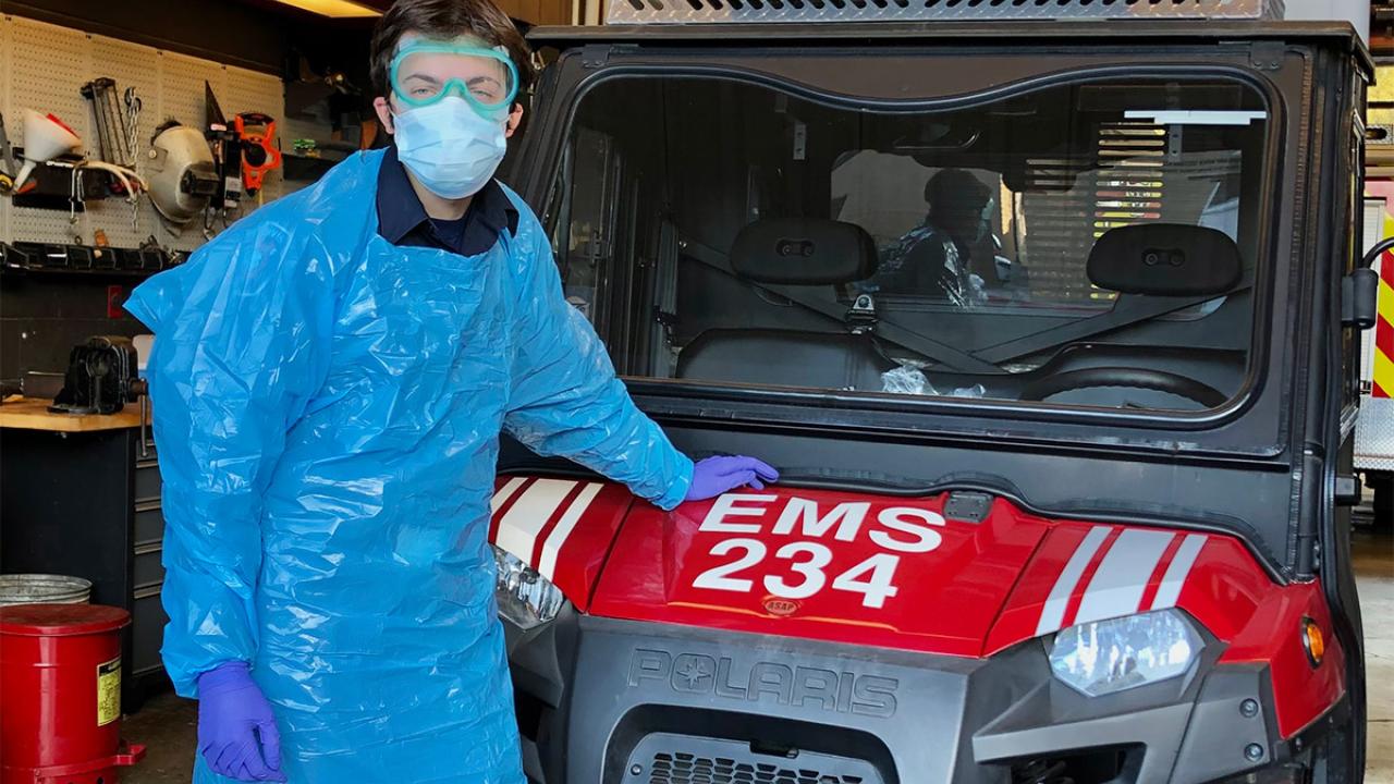 Student in protective gear stands next to ATV.