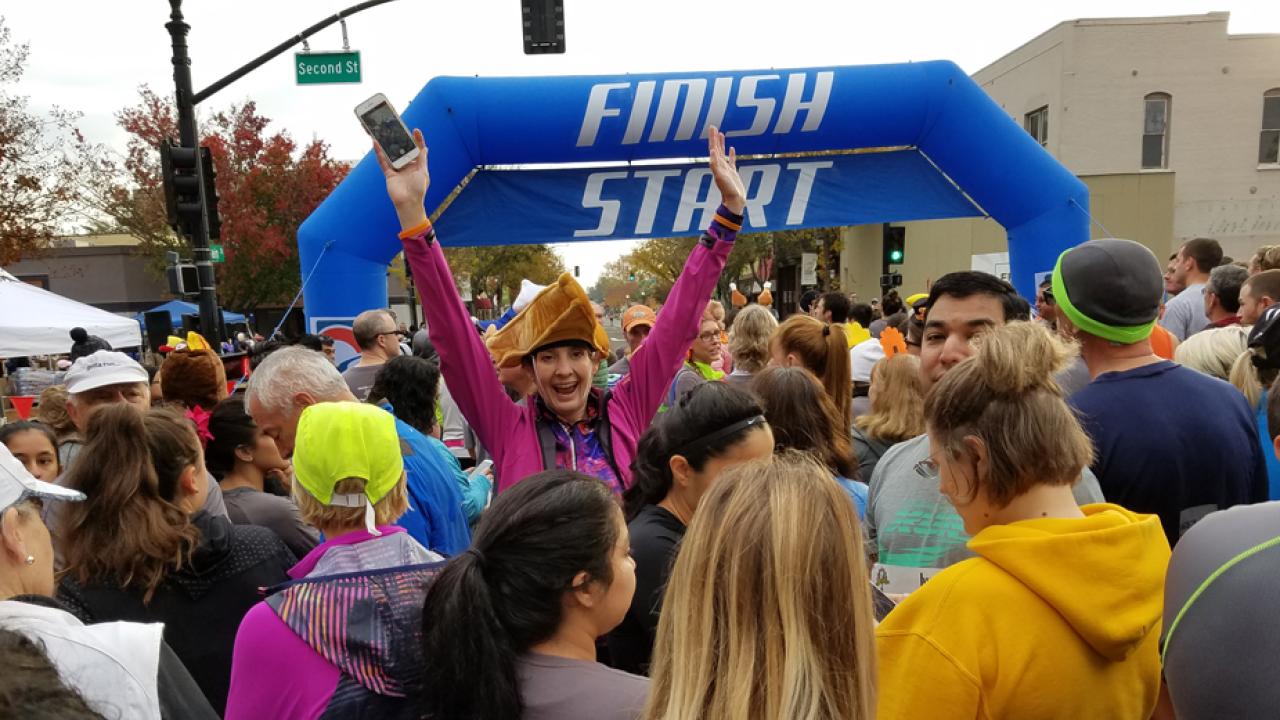 Woman in pie hat raises her arms in joy.