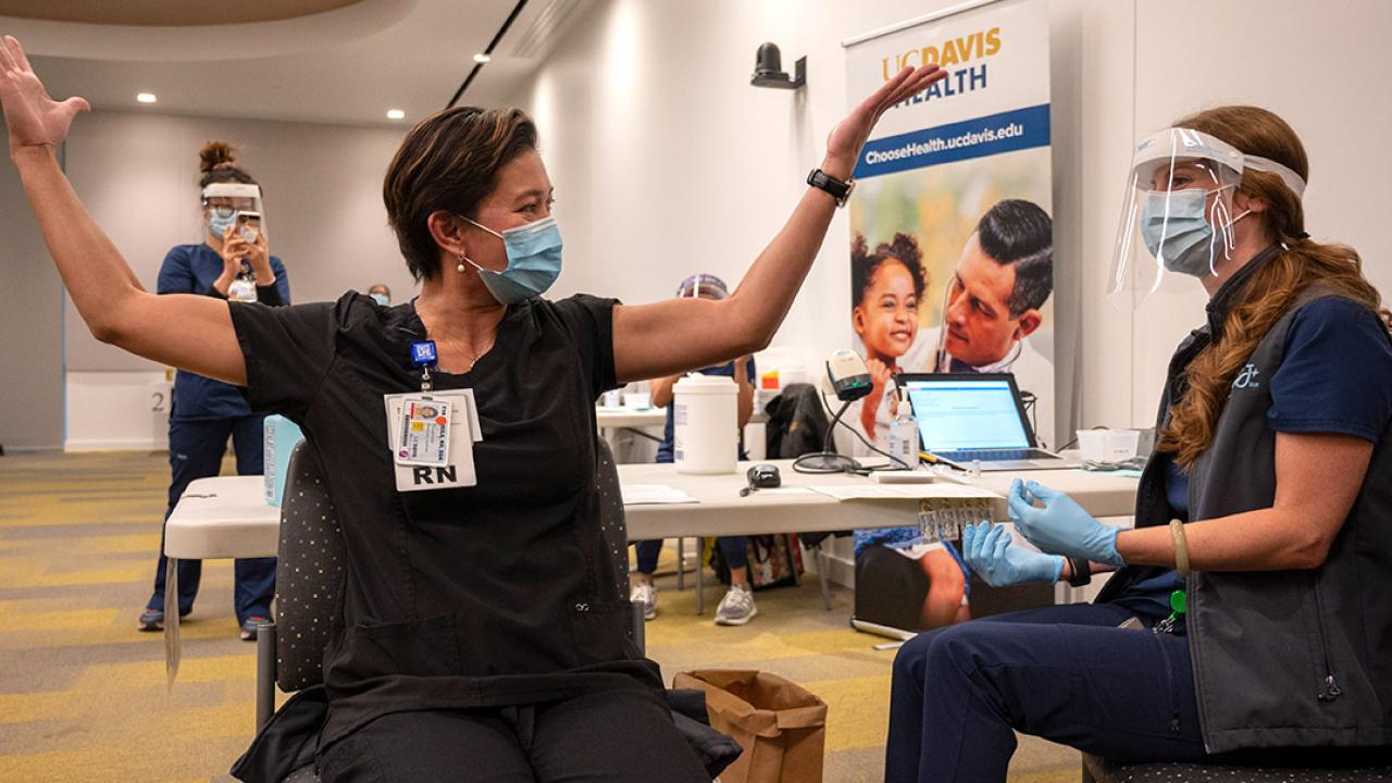 Woman lifts arms in celebration after receiving vaccine.