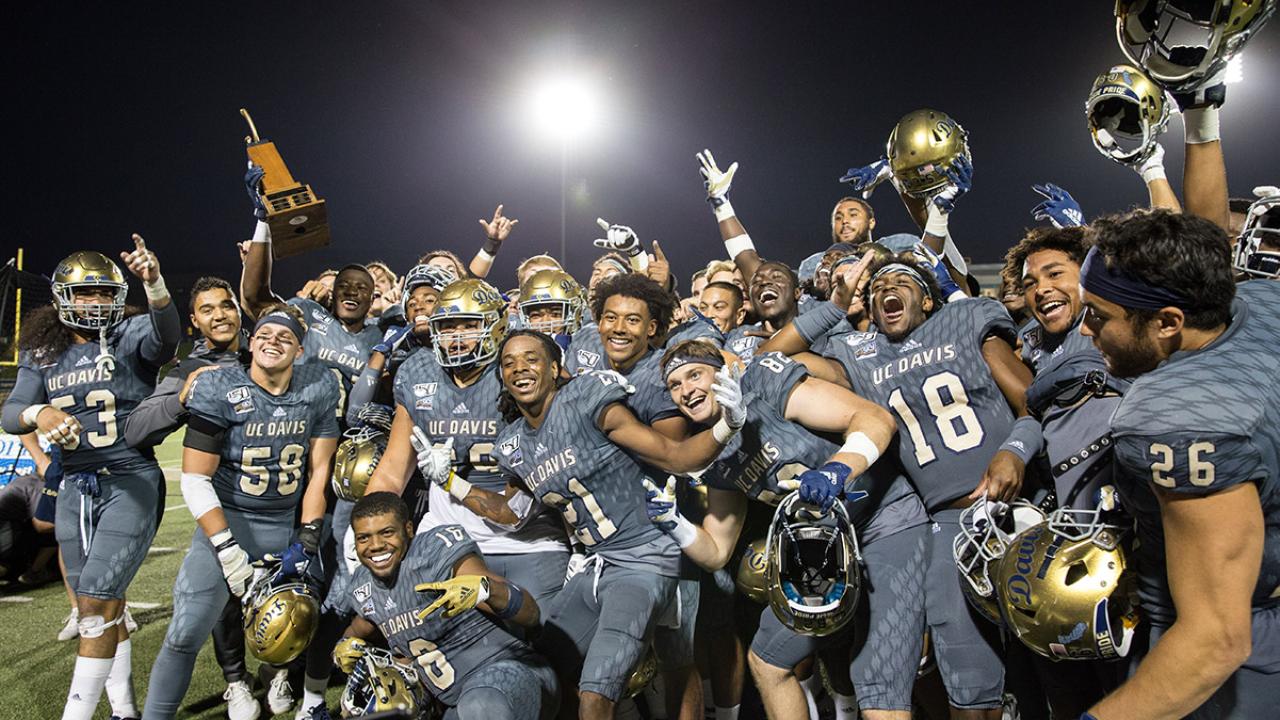 Football players celebrate and pose with the Golden Horseshoe trophy.