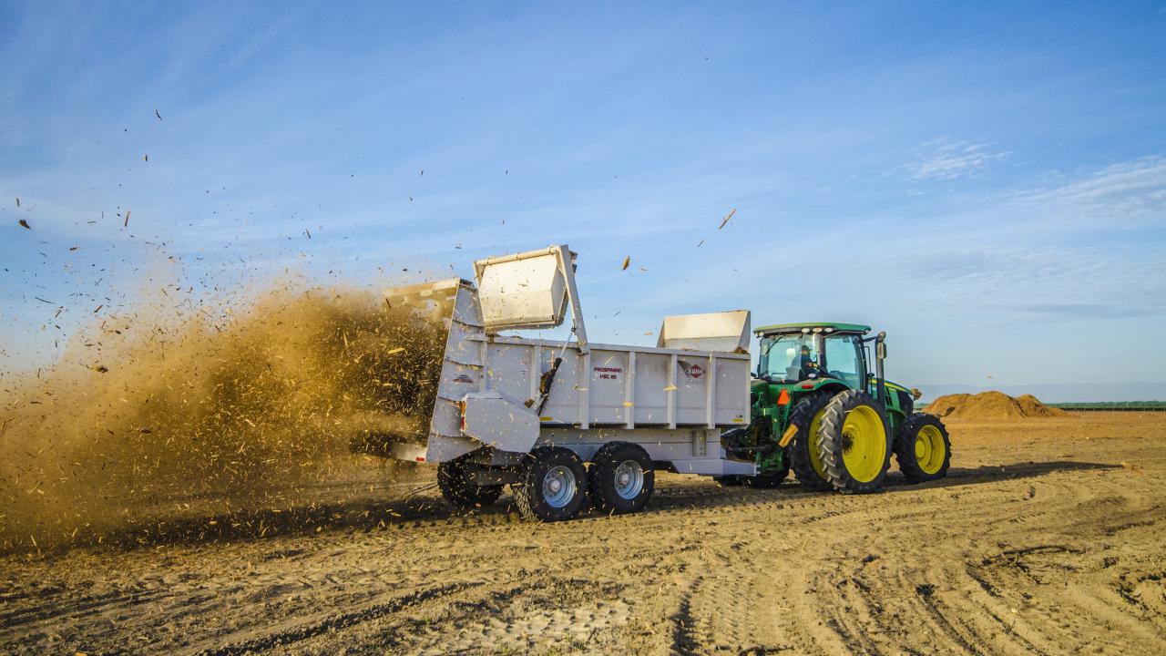 Wood chips from recycled almond trees spread across orchard by truck