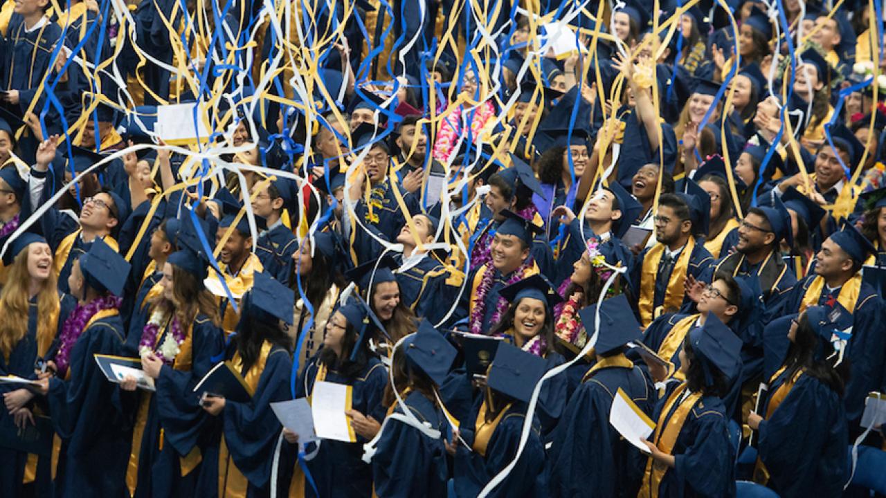 Streamers fall on graduates in caps and gowns.