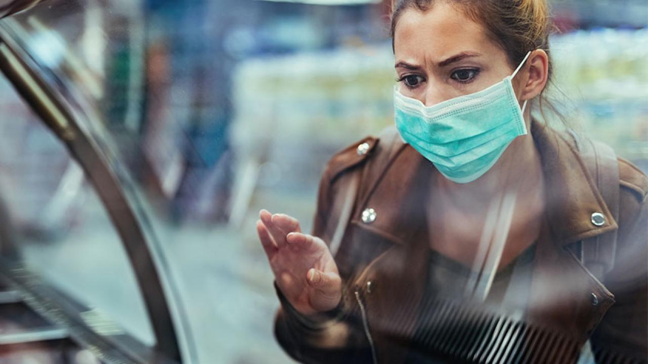 Masked woman looks at empty food display in grocery store