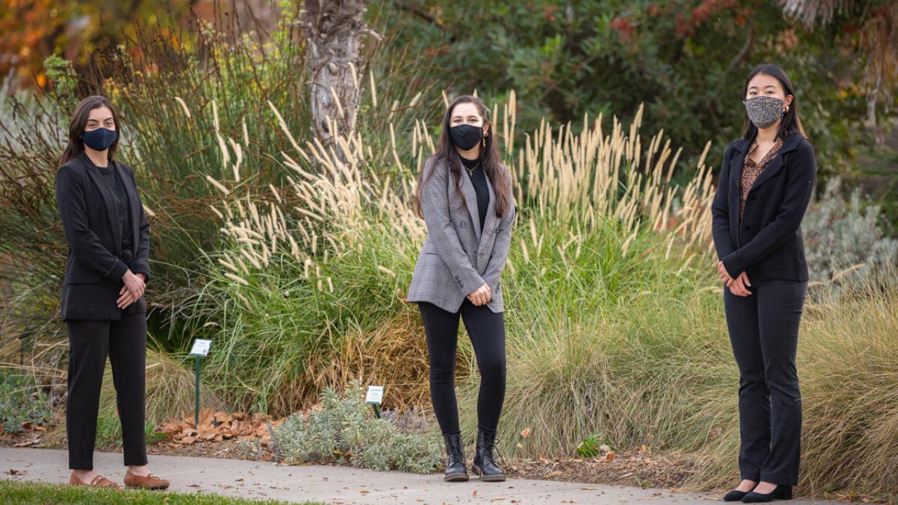 Three women, in masks, pose in Arboretum.