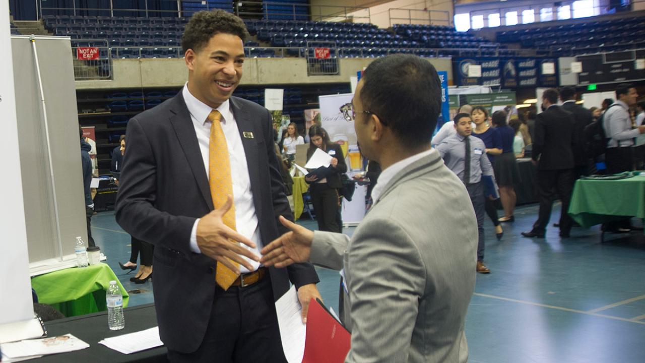 Two men in suits shaking hands at a career fair