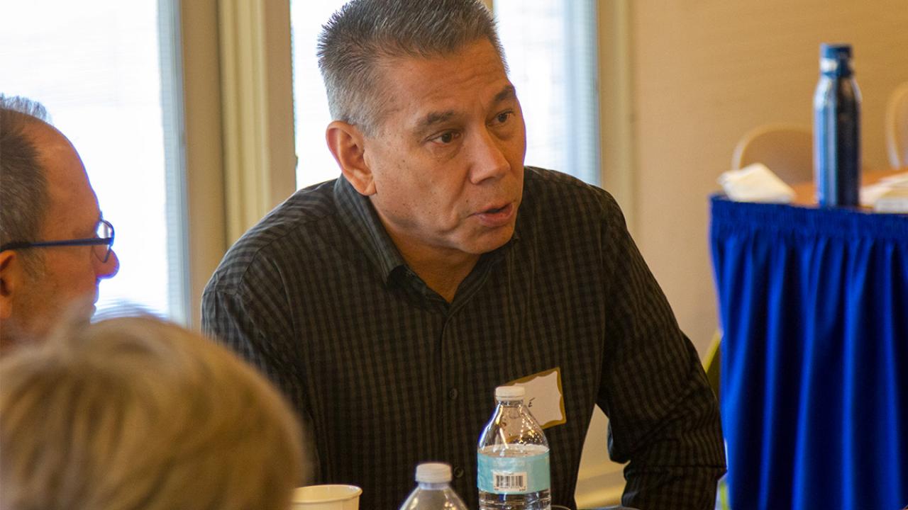 UC Davis Police Chief Joe Farrow sits at a table with other attendees.