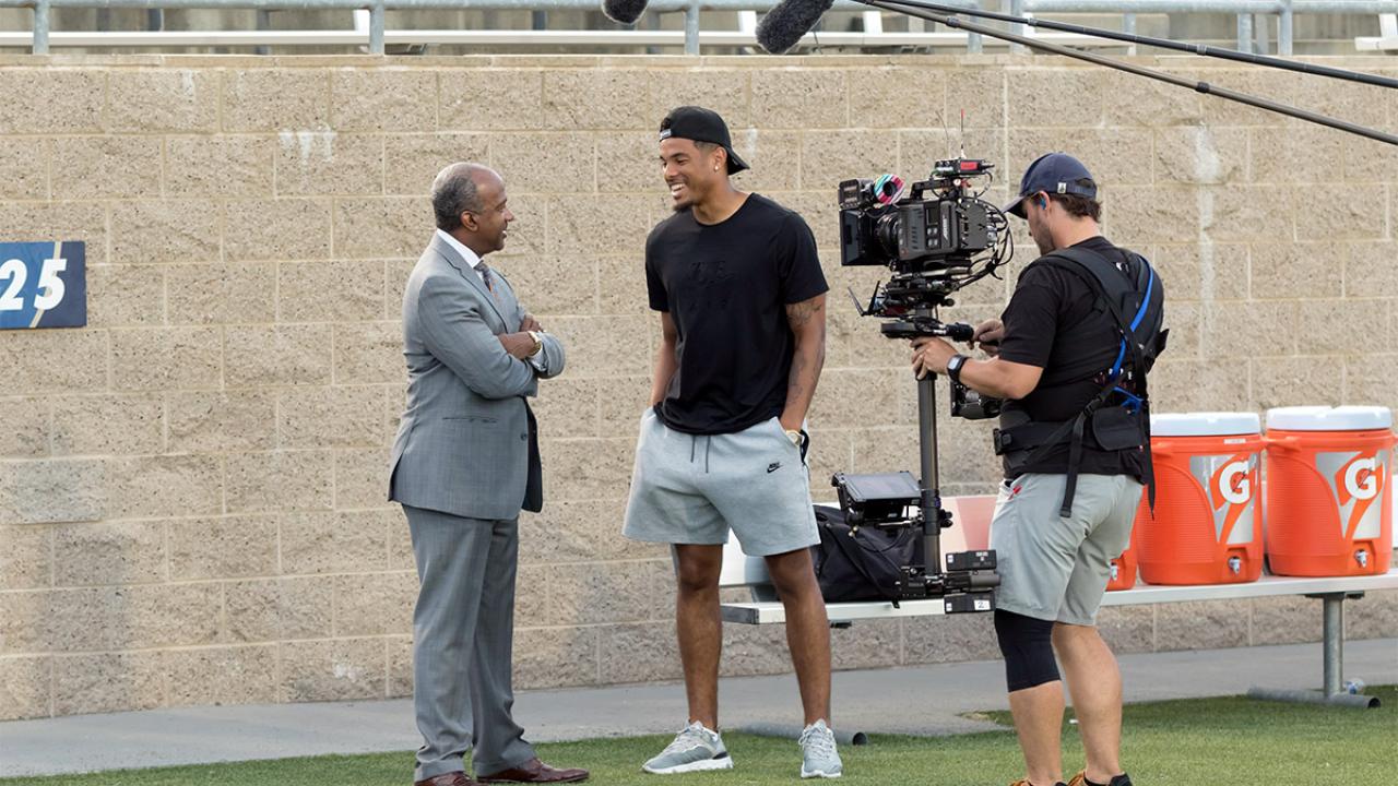 Chancellor Gary S. May speaks to Keelan Doss as a film crew records their conversation.