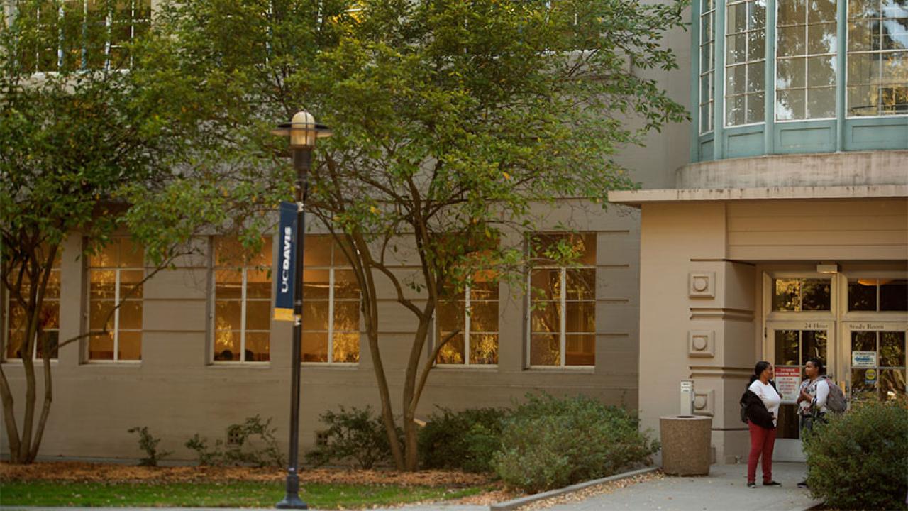 Two students stand outside the entrance to the UC Davis LIbrary's 24-Hour Study Room