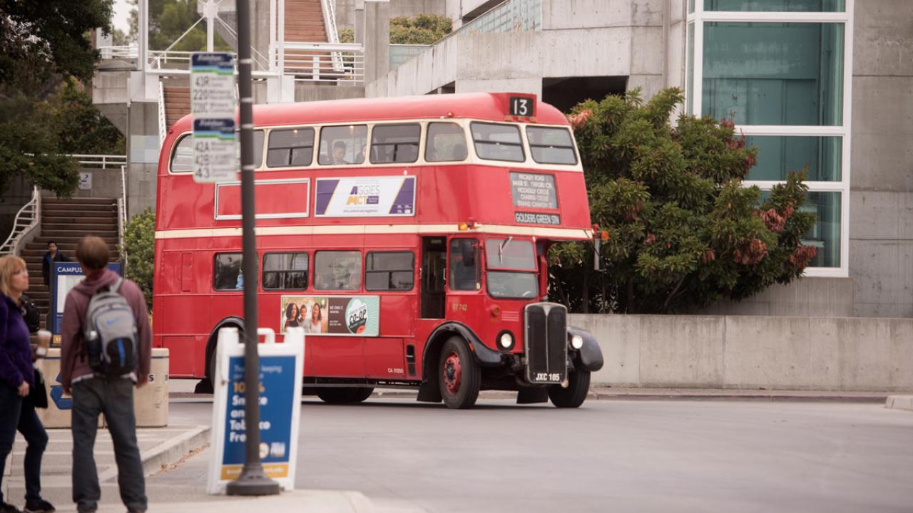 Red, vintage double-decker bus enters Memorial Union depot.