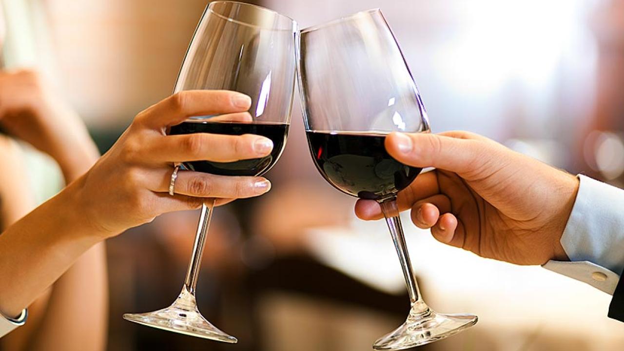 Hands of couple toasting with glasses or red wine.