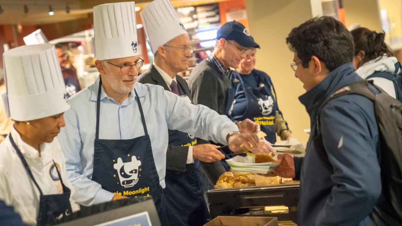 Campus leaders in tall, white chef's hats, serving breakfast.