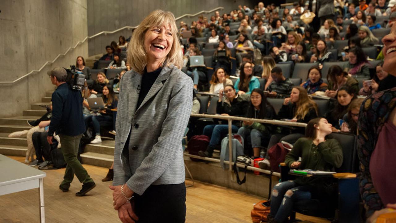 Professor Anita Oberbauer, smiling, in front of lecture hall filled with students.